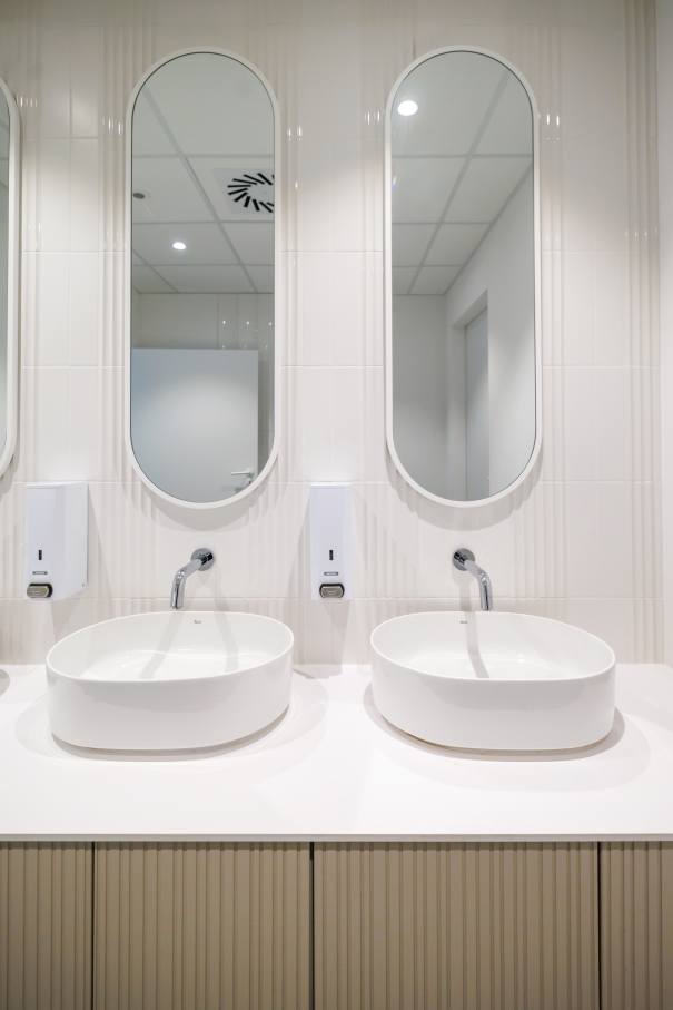The interior design of TriQube's bathrooms embraces a serene, minimalist aesthetic, with rounded shapes and a soothing colour palette creating a calming atmosphere. Chic urinals add a touch of distinction, offering both urban flair and unique appeal, while Access grab bars and Meridian toilets ensure accessibility and comfort. Roca products were carefully selected to enhance both the functionality and innovative spirit of the space, contributing to its high standards of quality and design.