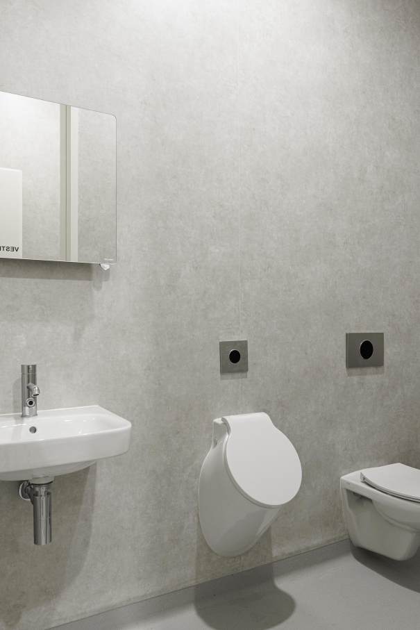 Accessibility and well-being extend beyond the building itself. Extensive green spaces, landscaped walking paths, and outward-facing windows bring calm to an otherwise clinical setting. Roca's bathroom solutions reinforce this philosophy throughout. White ceramic wall-hung Victoria toilets with Roca Rimless® technology and individual Debba ceramic basins introduce soft, rounded forms that blend seamlessly with the muted off-white interiors, creating a tranquil, monochrome atmosphere. Spun urinals with covers integrate discreetly and practically for all users. Together, StudioCAN's bold yet understated architecture and Roca's carefully chosen products deliver a healthcare environment where design is always in service of the people who use it.5